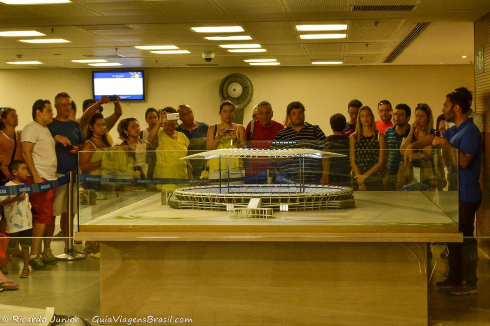 Imagem de vários turistas vendo a maquete do Maracanã.